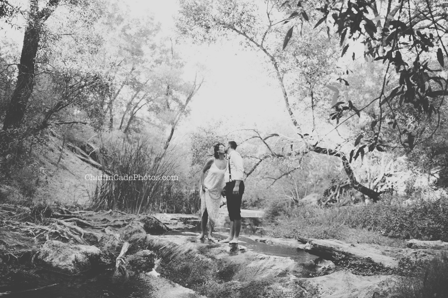 a black and white photo of a new husband and wife kissing in the middle of a creek in Malibu, CA