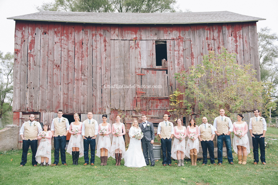 Ginger, Mike and their entire bridal party stand together in front of a large red barn