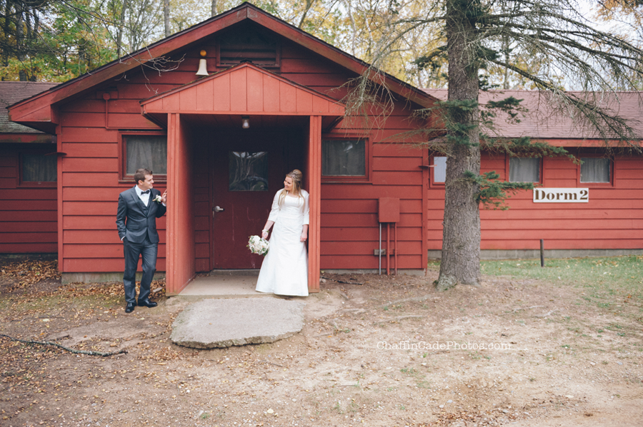 Ginger and Mike share a moment in front of a bright red dorm on their camp wedding day